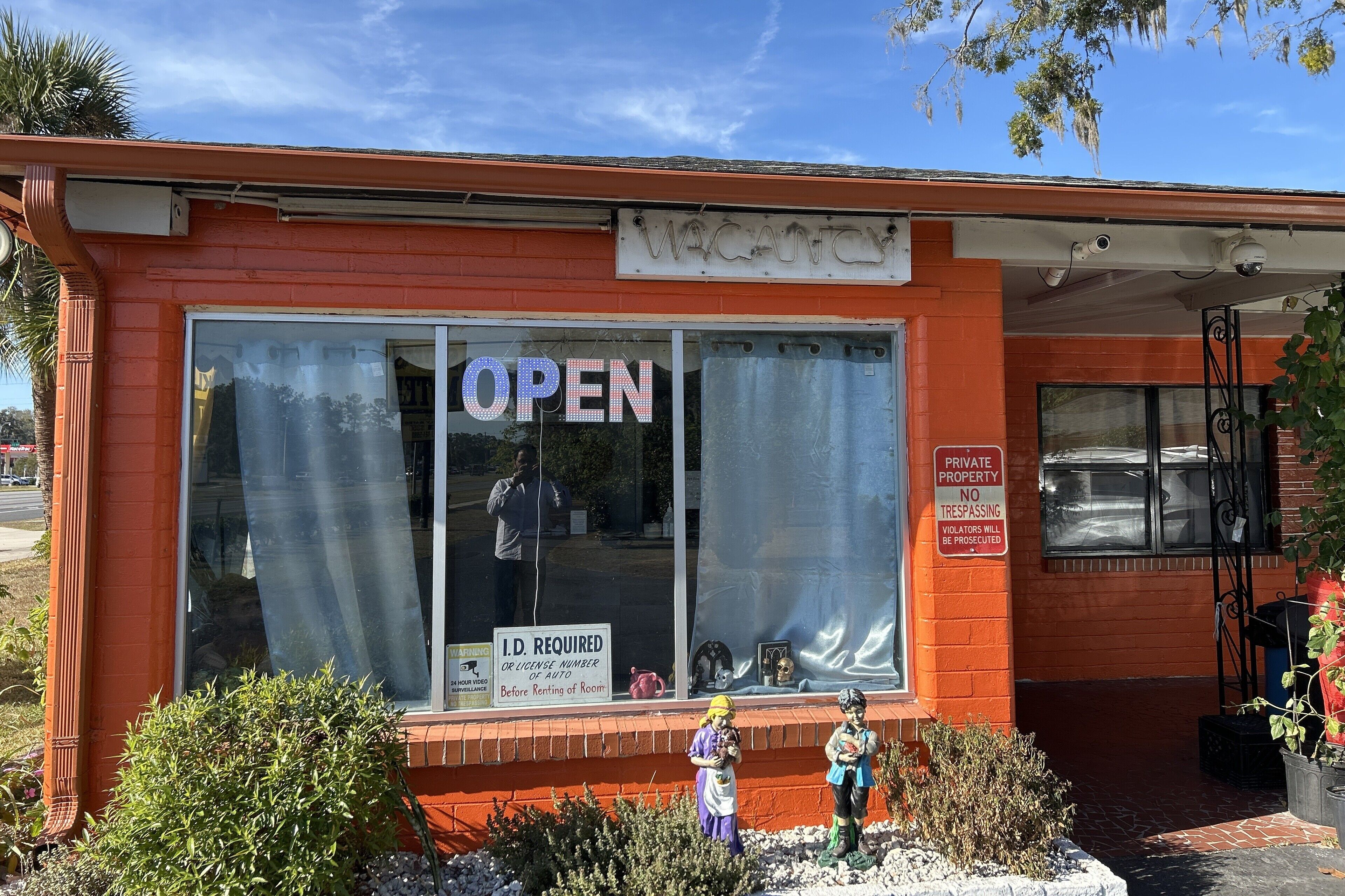 A building with a large window displaying 'OPEN' and a sign indicating 'I.D. REQUIRED OR LICENSE NUMBER OR AUTO' for entry.