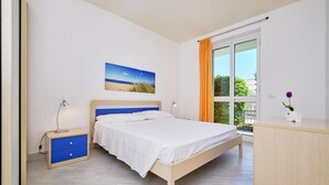 A bedroom with a bed, bedside tables, a desk, and a window with curtains. - Eolo, holiday home with garden 100 mt from the sea (Marina di Ragusa)
