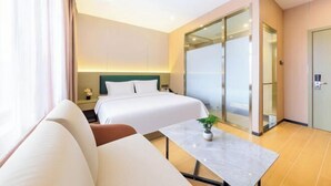Een hotelkamer met een bed, een slaapbank, een klein tafeltje met een plant, een nachtkastje en een schuifdeur.