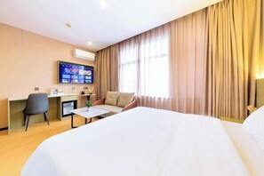 Ein Hotelzimmer mit Bett, Schreibtisch, Stuhl und Fernseher an der Wand.