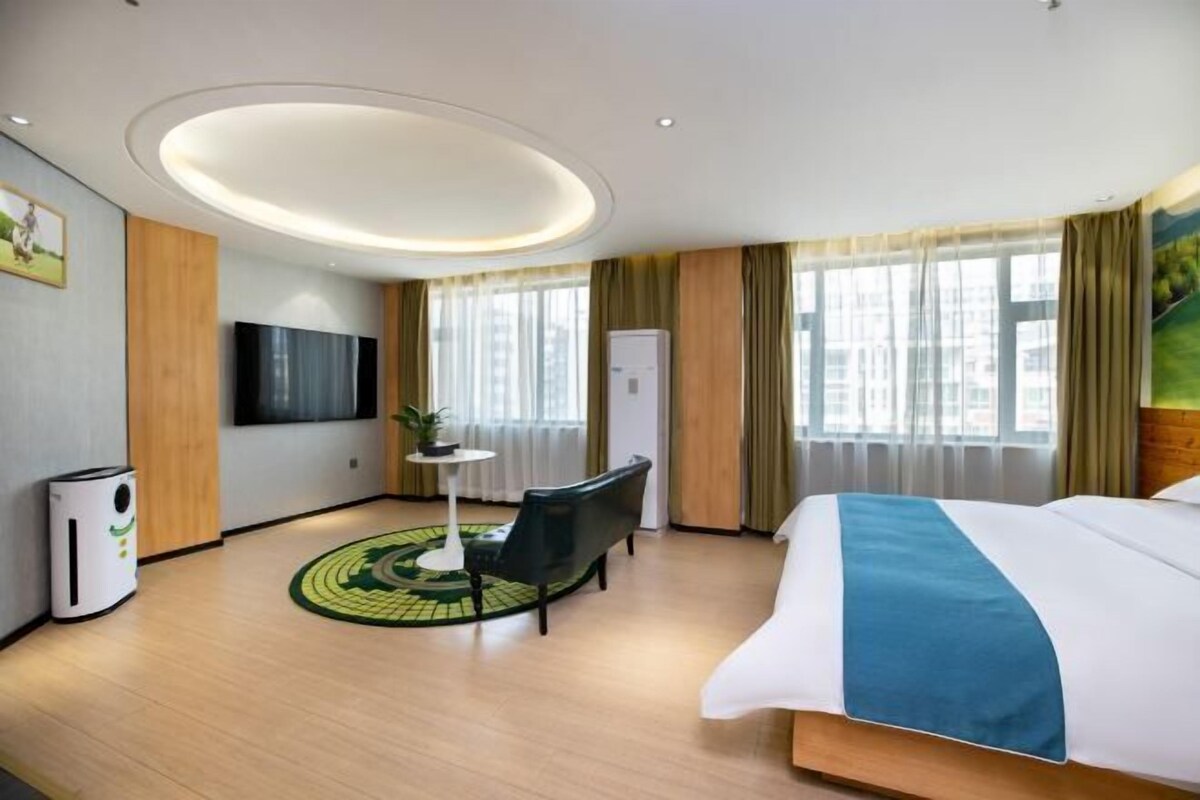 Ein Hotelzimmer mit Bett, Schreibtisch, Stuhl, Fernseher und einem fensterbepflanzten Fenster.