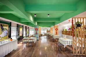 A restaurant with a green ceiling, wooden floors, and tables set for dining.