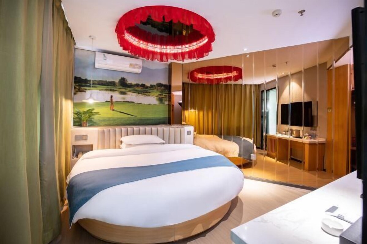 Ein Hotelzimmer mit einem großen Bett, einem Fernseher, einem Schreibtisch und einem Wandbild eines Golfplatzes.