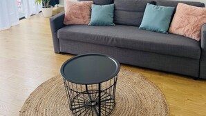 A modern living room with a grey sofa, a round black coffee table, and a large potted plant. - Maison 50 m2, à 5 Minutes de Paris et Idéal Pour Disney (Montreuil)
