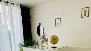 A bedroom with a bed, pillows, a globe, a mirror, and a shelf with plants. - Maison 50 m2, à 5 Minutes de Paris et Idéal Pour Disney (Montreuil)