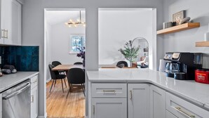 A modern kitchen with white cabinets, a marble countertop, and a coffee machine. - Hot Tub - Game Room - Sleeps 10 - Akron (Akron)