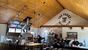 Un interno di ristorante con soffitto in legno, un forno per pizze e un bancone con scatole di pizza.
