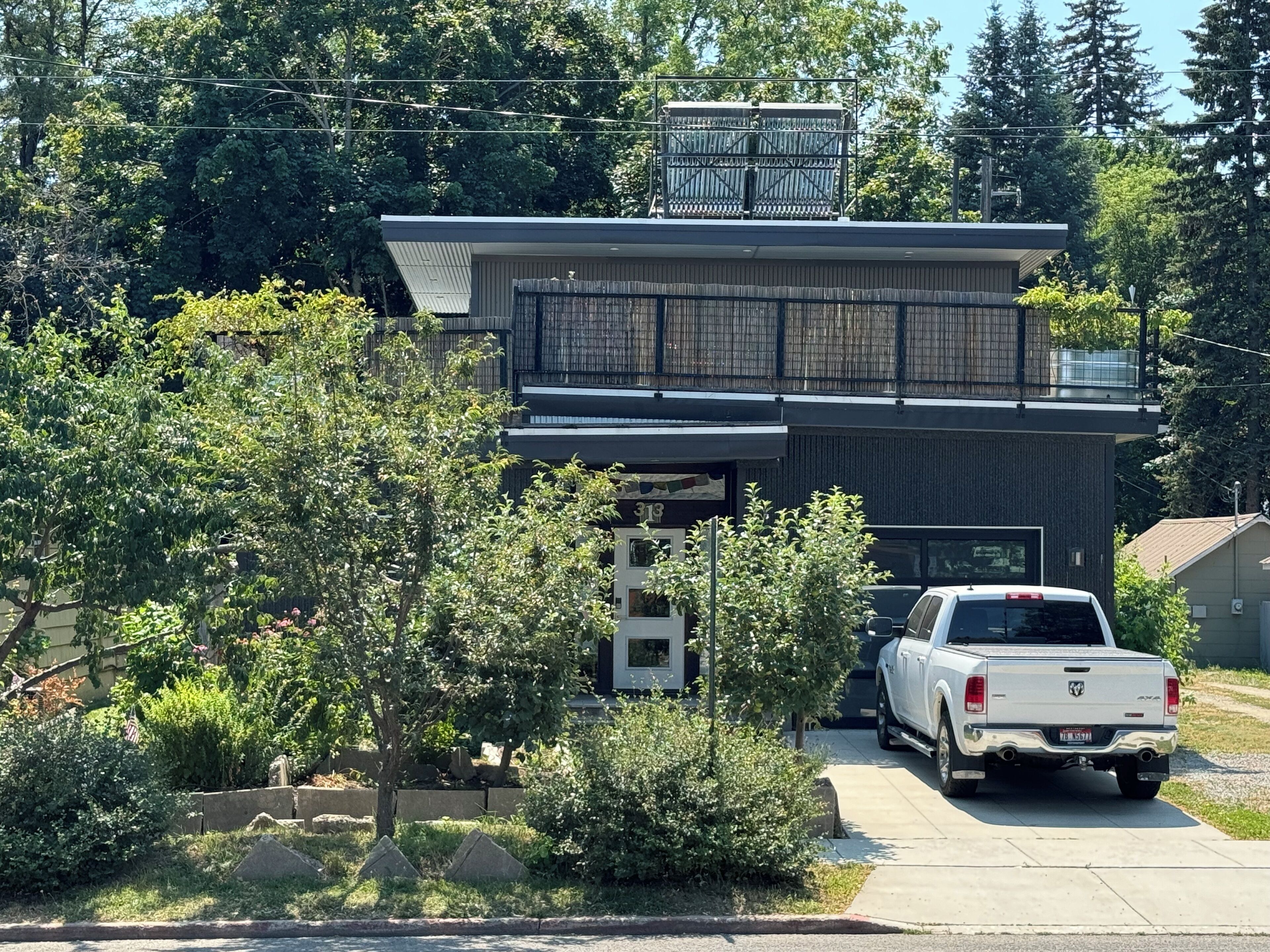 Ein modernes, zweistöckiges Haus mit Garage, voran ein weißer Pick-up geparkt ist.