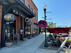 An outdoor seating area with tables and chairs in front of a building with a sign reading "PENDLE WINE BAR".