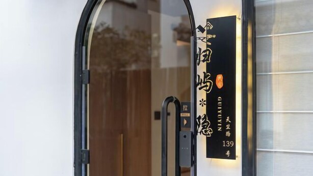 A hotel entrance with a glass door and a sign displaying the name and address. - Guiyu·Yin (Hangzhou)