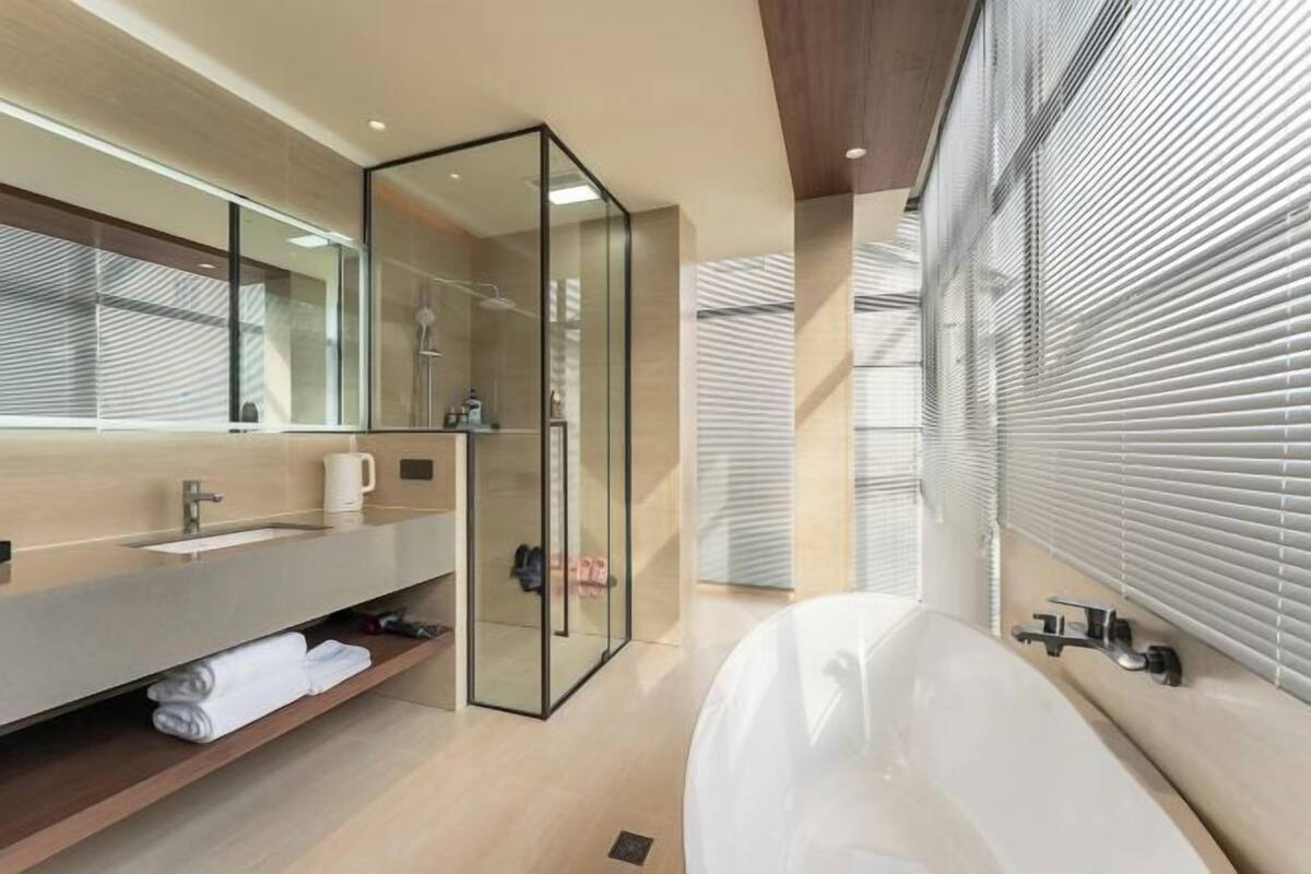 A modern bathroom with a large bathtub, a glass shower enclosure, and a wooden vanity.