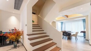 A modern interior with a wooden staircase, a dining area, and a reception desk. - Guiyu·Yin (Hangzhou)