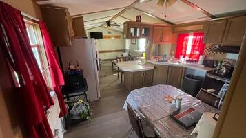Een kleine keuken met een koelkast, fornuis, magnetron en een eethoek.
