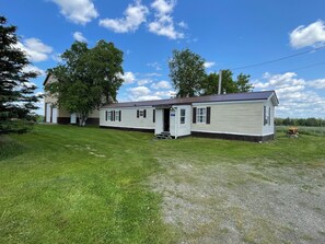 A single-story mobile home with a porch, a garage, and a small garden area.