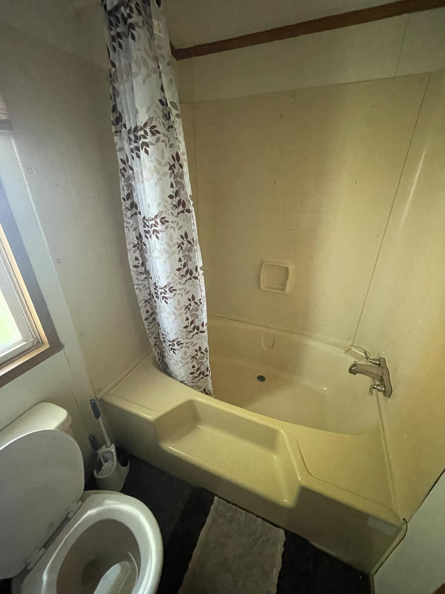 A bathroom with a toilet, a shower with a floral curtain, and a sink.