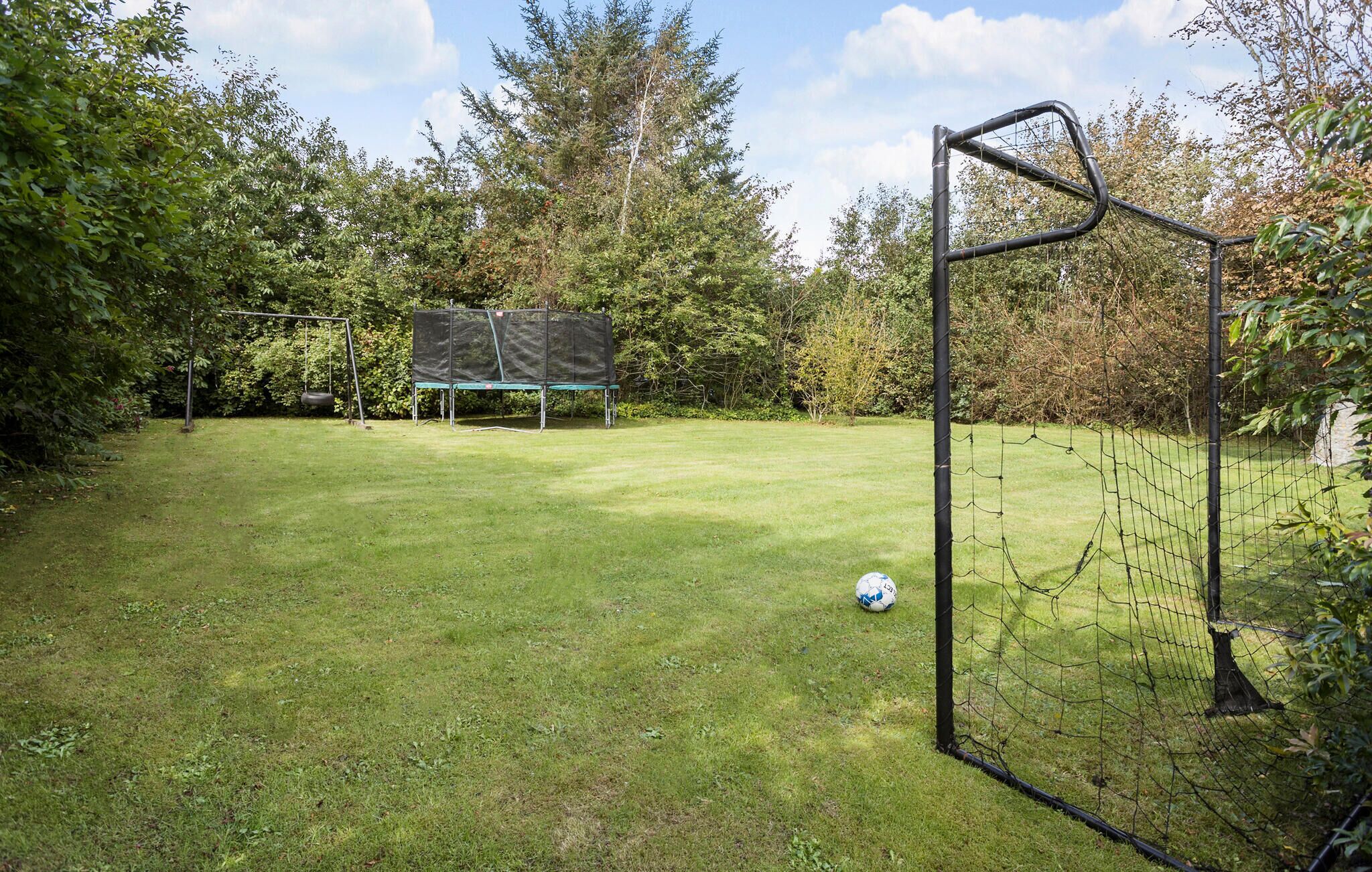 Ein Garten mit Rasenfläche, Fußballtor, Trampolin und Schaukel.