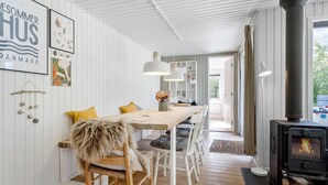 A cozy dining area with a wooden table, white chairs, and a rustic decor including a fur chair and wall art. - Pet friendly home in Spøttrup with WiFi (Spøttrup)