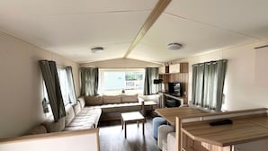 L’intérieur d’une caravane, avec un ensemble de canapés, une table à manger et un téléviseur.