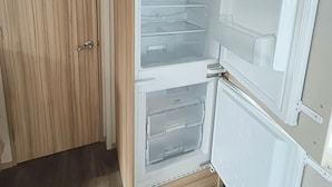 Une pièce avec une armoire en bois, un réfrigérateur blanc et un meuble blanc.