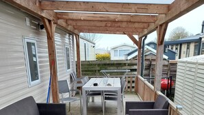 Un patio extérieur abrité, doté d’une table et de chaises, et entouré de meubles en osier.