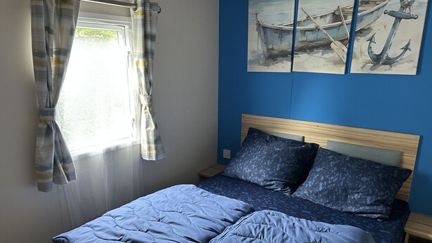 Une chambre à coucher avec un lit, des rideaux, une tête de lit et des œuvres d’art accrochées au mur.