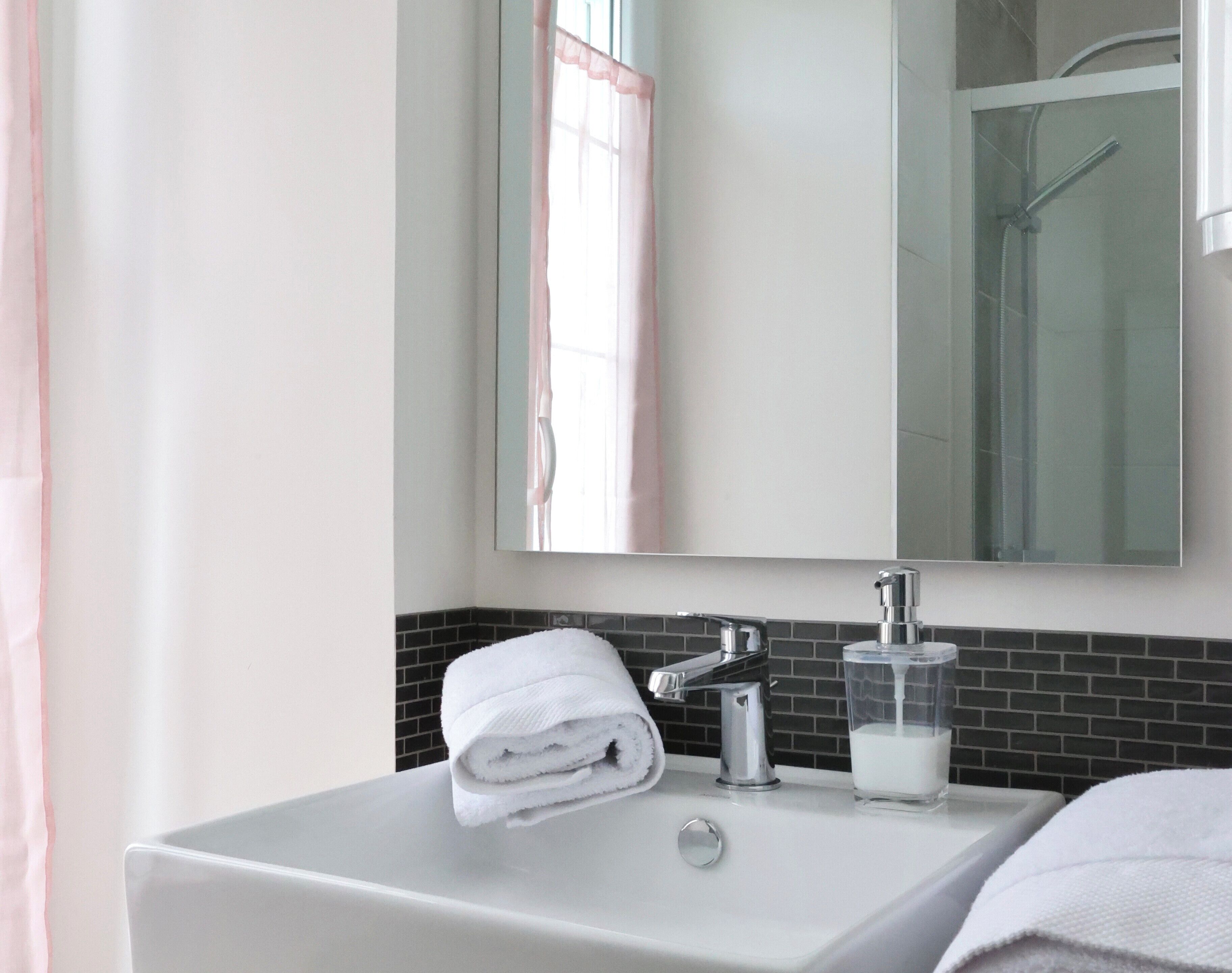 Une salle de bain avec un lavabo blanc, un miroir et un verre de lait.