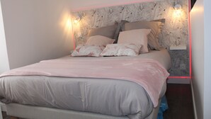 A bedroom with a bed, pillows, and a wall-mounted light fixture. - Le Flamingo - Wifi - 400m centre Pontivy (Pontivy)
