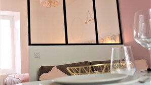 A neatly arranged dining area with a table set for two, a modern pendant light, and a large mirror reflecting the room's decor. - Le Flamingo - Wifi - 400m centre Pontivy (Pontivy)