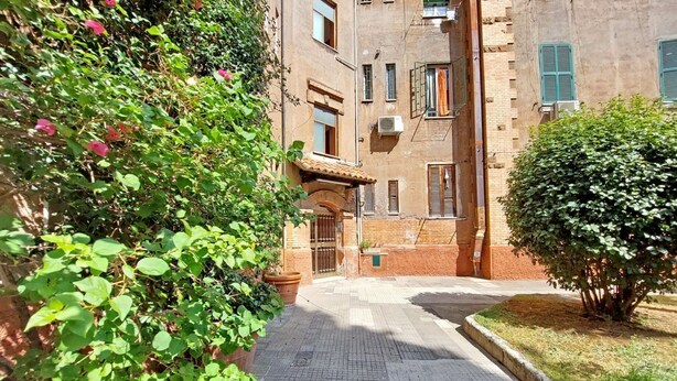 A narrow alleyway with a brick building, a potted plant, and a small tree. - Cozy and recently renovated apartment for 4 near the Vatican (Roma)