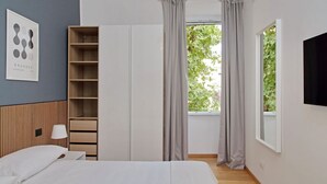 A bedroom with a bed, a wardrobe, a bedside table, a lamp, and a window with curtains. - Cozy and recently renovated apartment for 4 near the Vatican (Roma)
