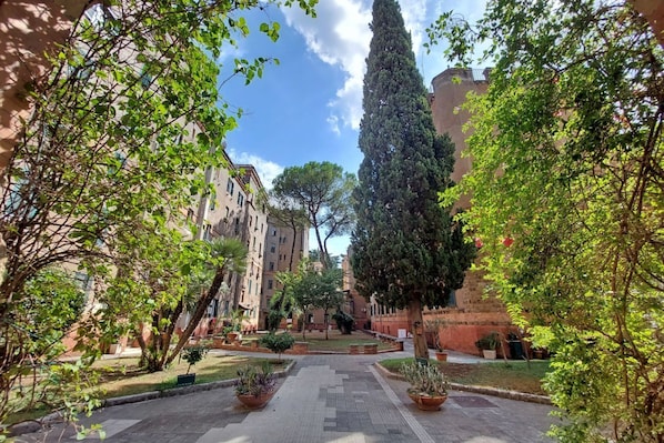 A courtyard with a central pathway, surrounded by buildings and greenery.