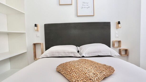 A neatly arranged bedroom with a large bed, two bedside tables with lamps, a headboard, and two framed pictures on the wall.