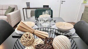 A dining table set with plates, bowls, and glassware, surrounded by chairs.