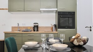 A modern kitchen with green cabinets, a built-in oven, and a coffee maker.