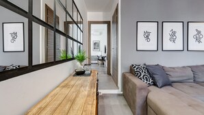 Un intérieur moderne avec un banc en bois, un canapé et des œuvres d’art encadrées accrochées aux murs.