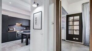 Une cuisine moderne avec des meubles de couleur sombre, une table à manger et un tableau encadré au mur.