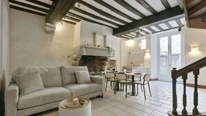 Una sala de estar acogedora con chimenea, un sofá y un comedor con sillas.