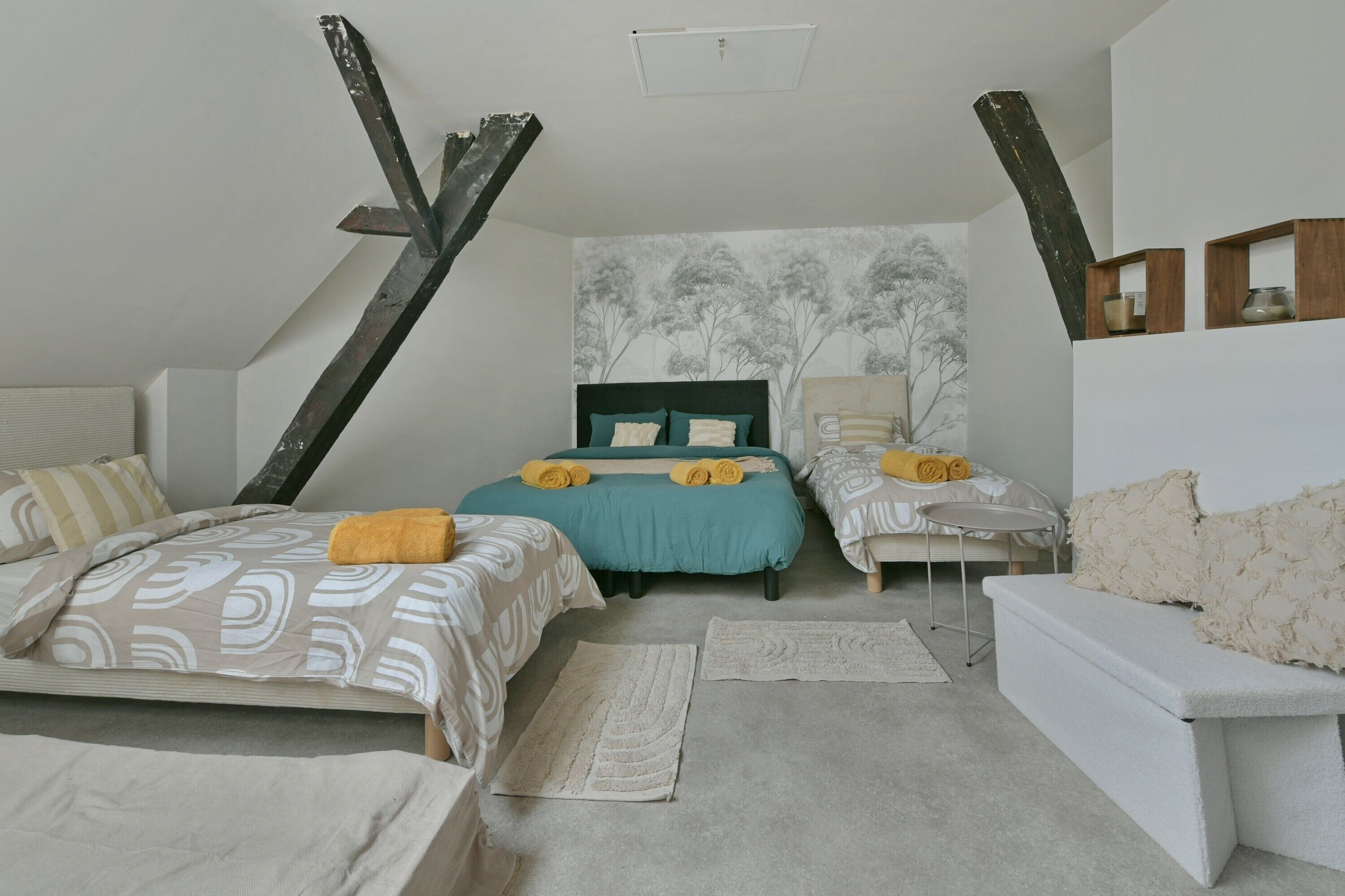 A bedroom with two beds, a sofa, a small table, and a wall-mounted shelf.