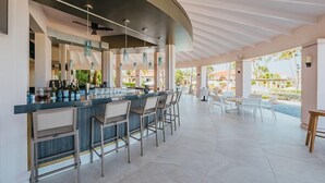 A modern bar area with a curved ceiling, bar stools, and a view of the outdoor patio. - Tierra del Sol Beach Home (Noord)