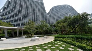 A modern building with a unique curved architecture, surrounded by a well-maintained garden with pathways and seating areas.