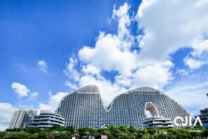 A modern hotel with a distinctive curved facade and a large central archway. - Q+ · Beihai Beibu Bay No.1 Yijia Online Serviced Apartment (Beihai)