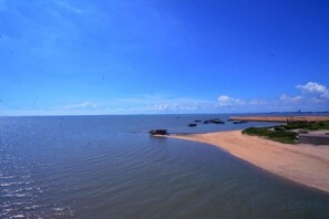 Une plage aux eaux calmes, avec un rivage sablonneux et un ciel dégagé.