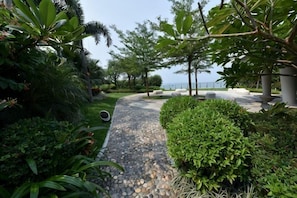 A landscaped garden with a stone pathway, lush greenery, and seating areas.