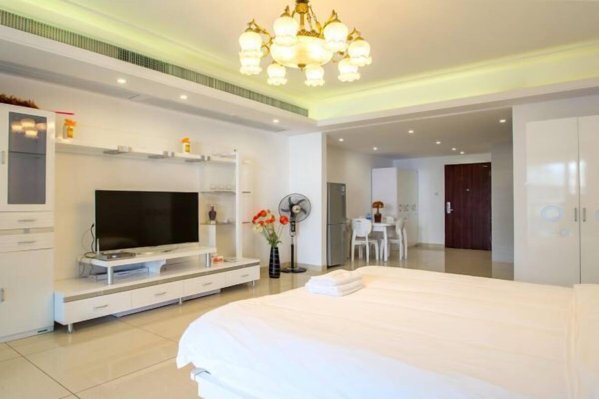 Una habitación de hotel moderna con una cama grande, televisión de pantalla plana, zona de comedor y vestidor.