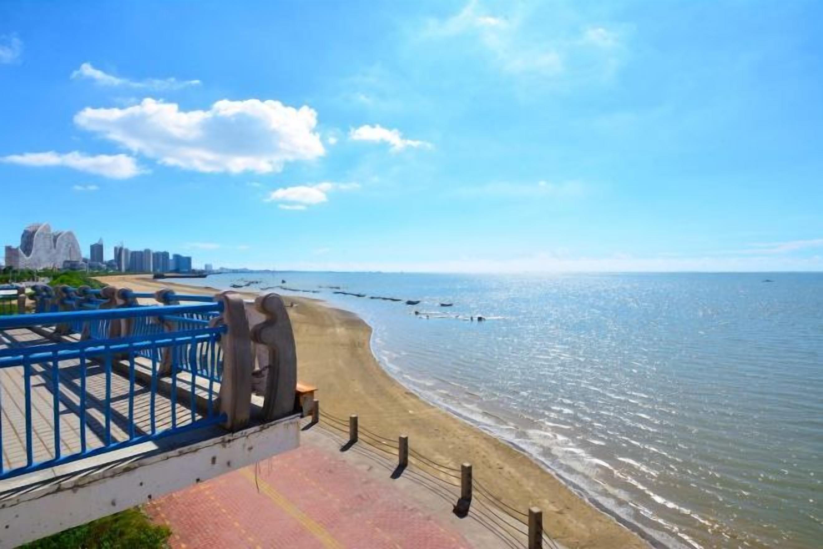 Uma praia com um calçadão azul e vista para o oceano.