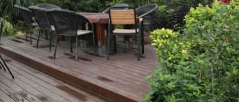 Una terraza exterior de madera con una mesa y sillas.