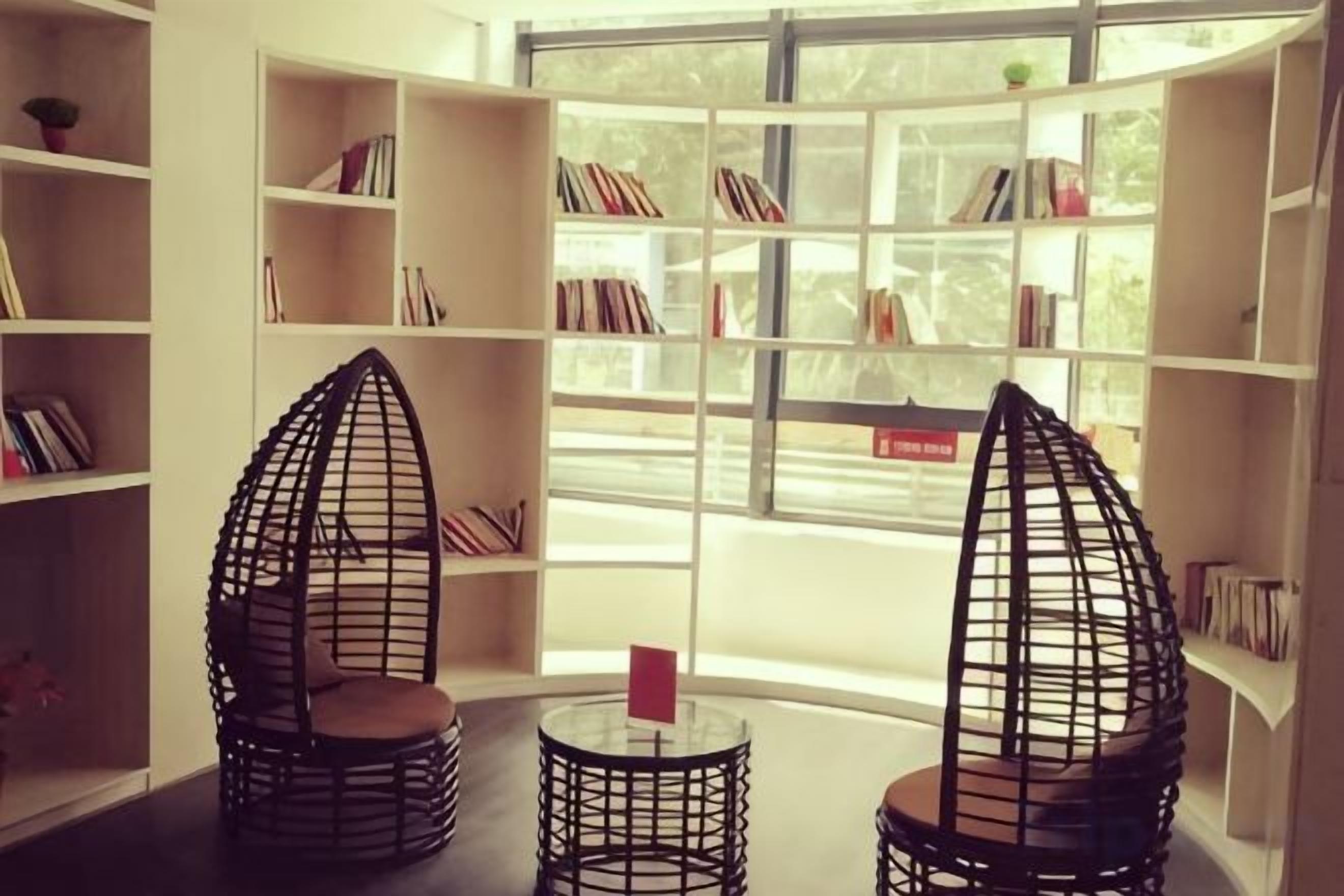 A reading area with two chairs and a table, surrounded by bookshelves.