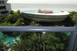 Un bâtiment circulaire doté d’une piscine, entouré de verdure et offrant une vue sur une étendue d’eau.