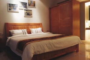 Un lit avec une tête de lit en bois, une literie blanche et un couvre-lit à motifs.