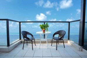 A balcony with a table and two chairs, overlooking a body of water. - Q+ · Beihai Beibu Bay No.1 Yijia Online Serviced Apartment (Beihai)